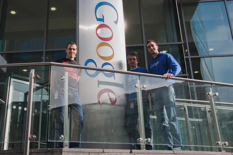 three-google-employees-standing-next-to-google-building-logo-in-dublin.webp
