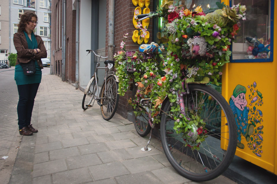 woman-looking-at-dutch-bicycle-covered-with-leaves.webp